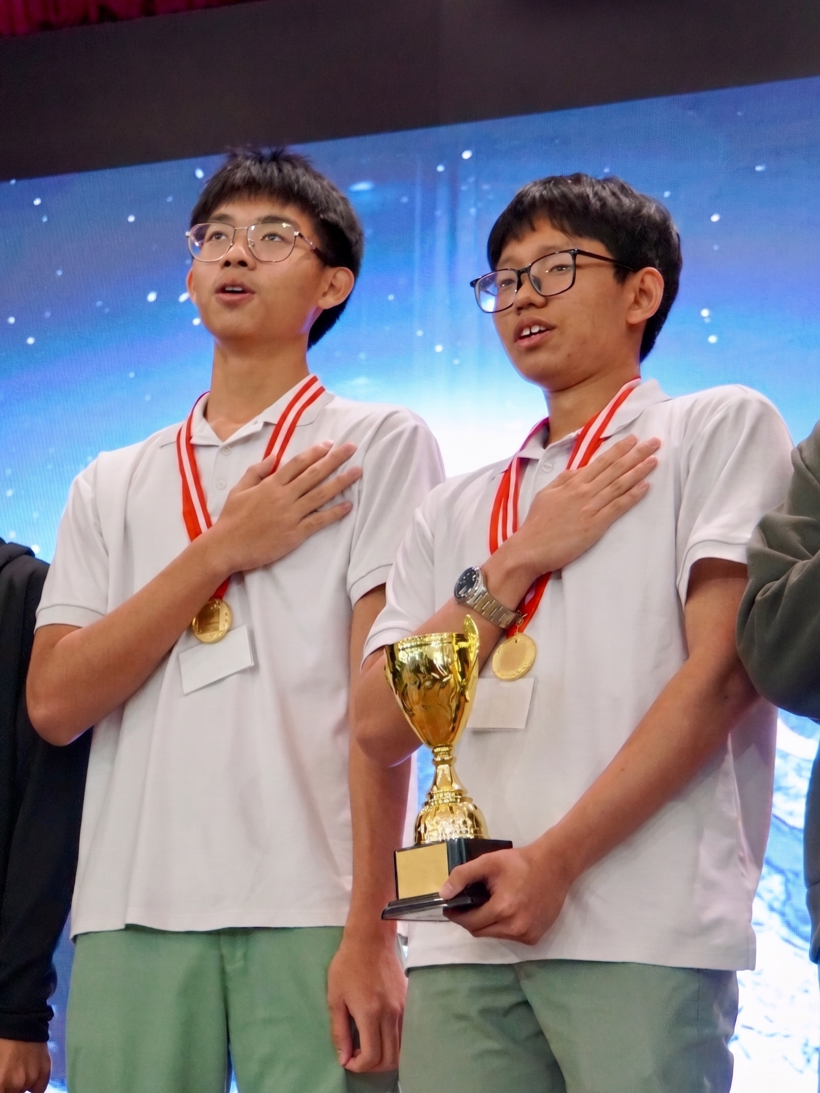 Allen and Jaden standing side by side, hands over their hearts